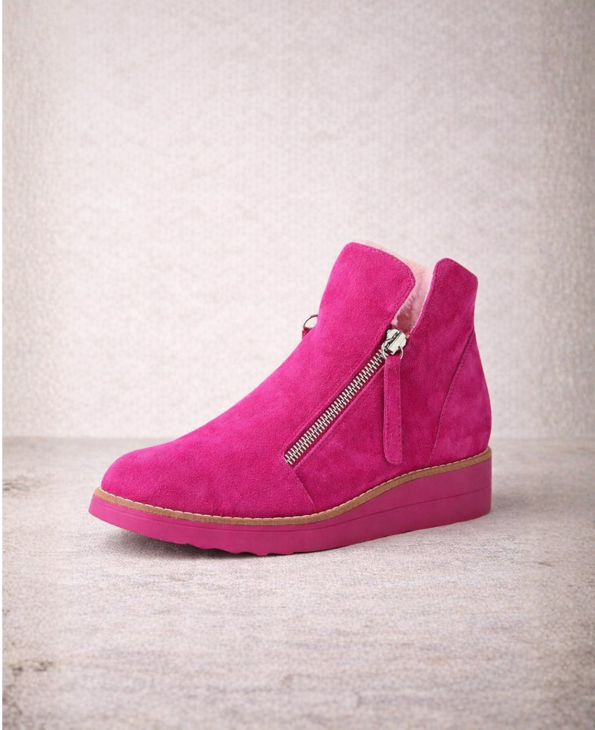 Angled view of Opal fuchsia suede ankle boots highlighting the zip fastening, wedge sole and warm faux fur lining.