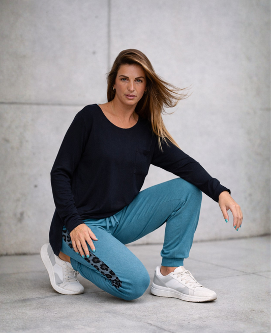 Model wearing Paris Knit Jogger pants in teal with leopard side stripe styled with sneakers in a modern concrete urban setting