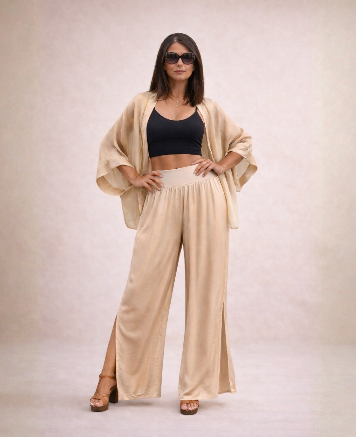 Front view of Pippa Silk Pants in Caramel silk blend, styled with matching short duster and black cropped tank top, both hands on hips and wearing sunglasses.