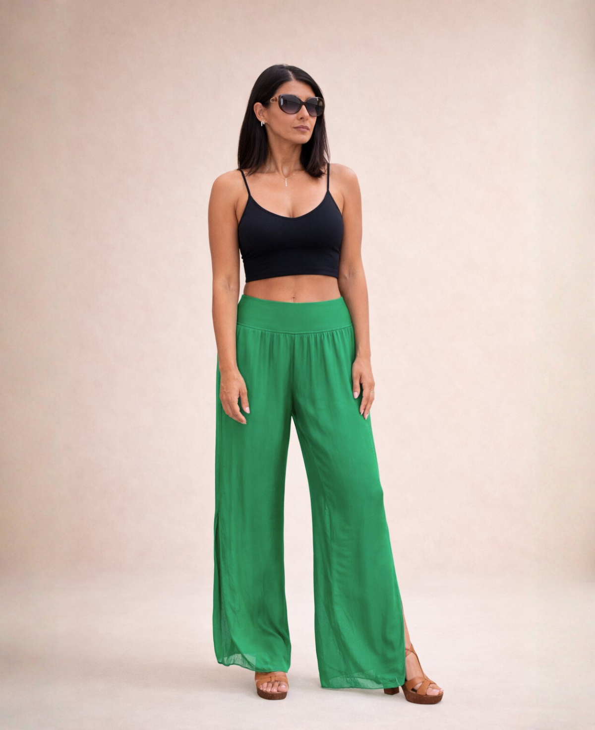 Front angled view of Pippa Silk Pants in Emerald silk blend, styled with black cropped tank top and sunglasses in studio.