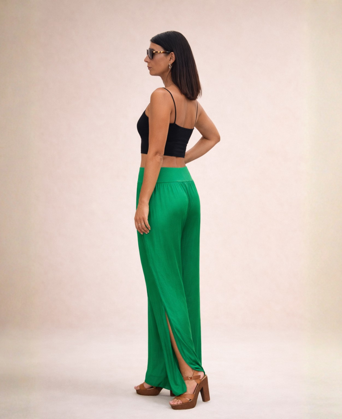 Back angled view of Pippa Silk Pants in Emerald silk blend, styled with black cropped tank top and sunglasses in studio.
