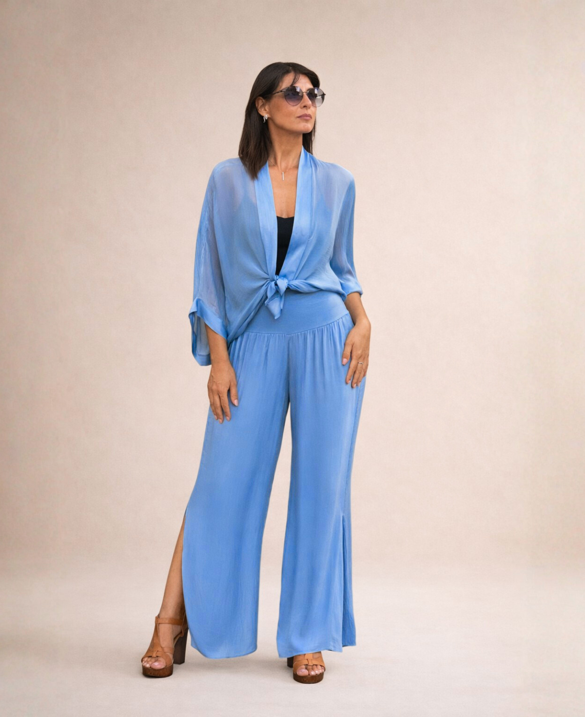 Front view of Pippa Silk Pants in Jeans blue silk blend, styled with matching silk short duster tied at the front over black cropped tank top, wearing sunglasses.