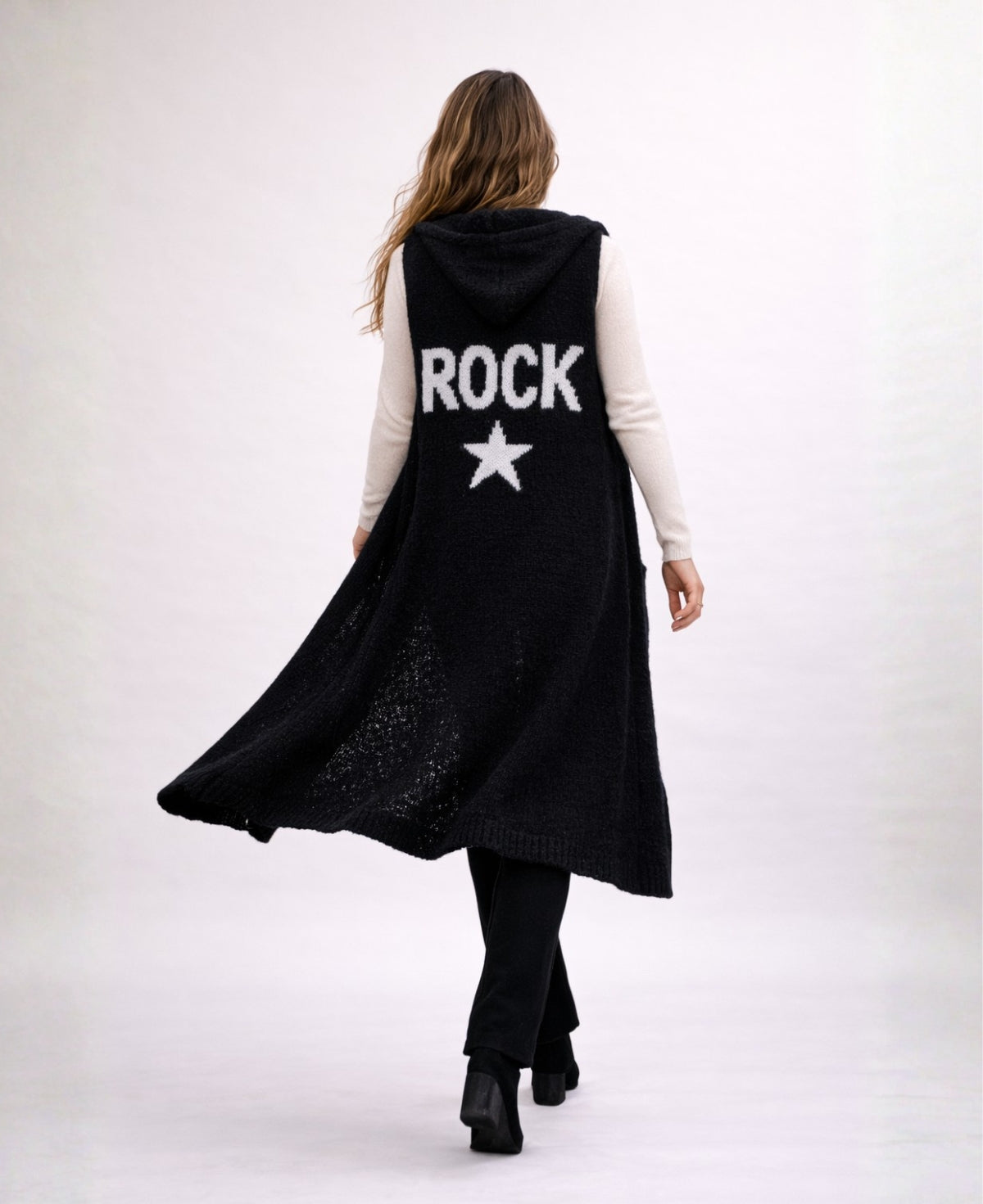 Back studio view of the Rockstar Long Vest in black featuring white ROCK graphic and star, styled with the Le Coco Sweater in cream and Bribie black knit pants.