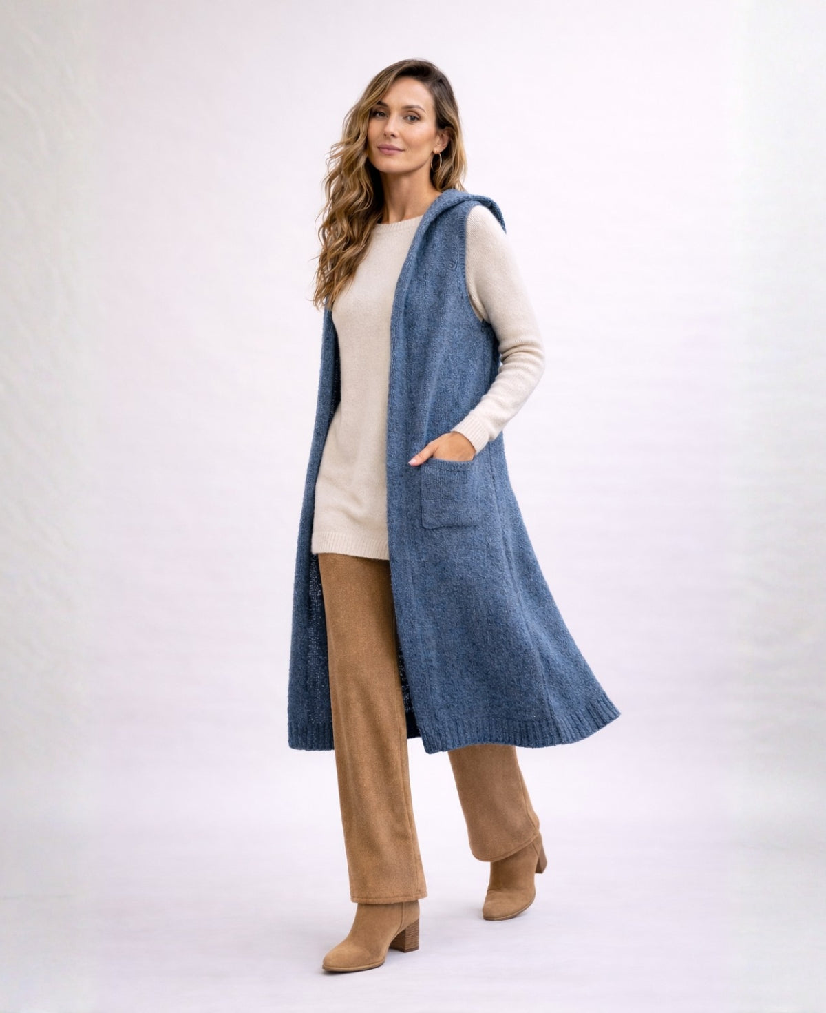 Front angled studio shot of the Rockstar Long Vest in blue styled with the Le Coco Sweater in cream, Bribie camel knit pants and tan suede ankle boots.