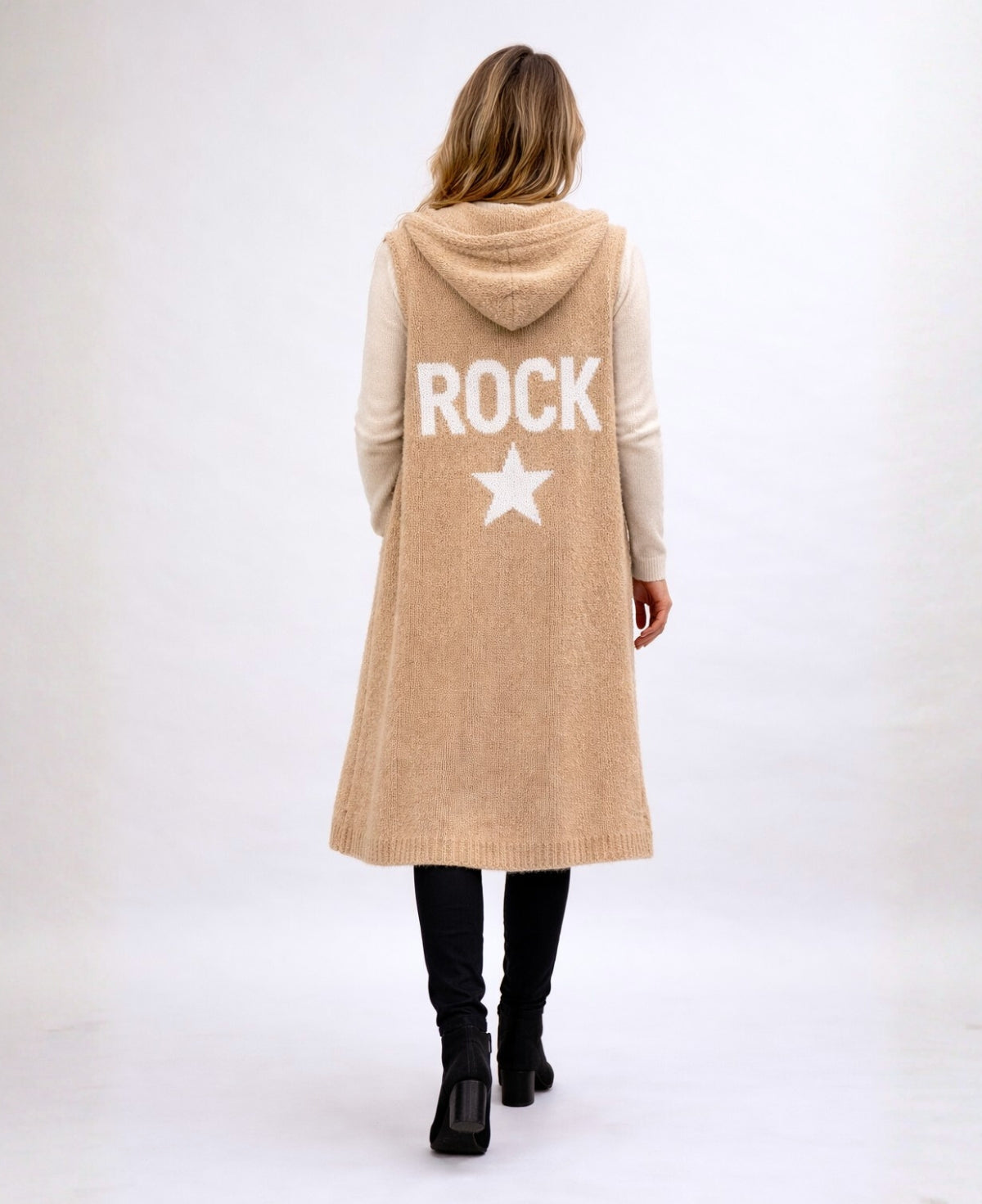 Back studio view of the Rockstar Long Vest in camel featuring the white ROCK and star knitted graphic, styled with the Le Coco Sweater in cream, straight black pants and black suede ankle boots.