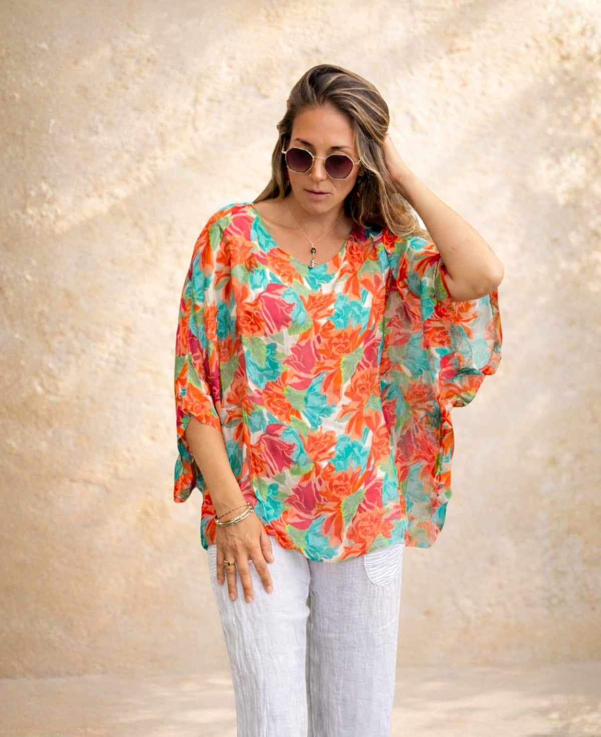 Model wearing the Roses Silk Top in rose floral print with relaxed batwing sleeves and white linen pants.