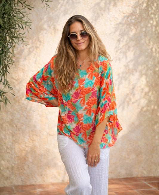 Model wearing the Roses Silk Top in rose floral print styled on a Mediterranean terrace with relaxed summer styling.