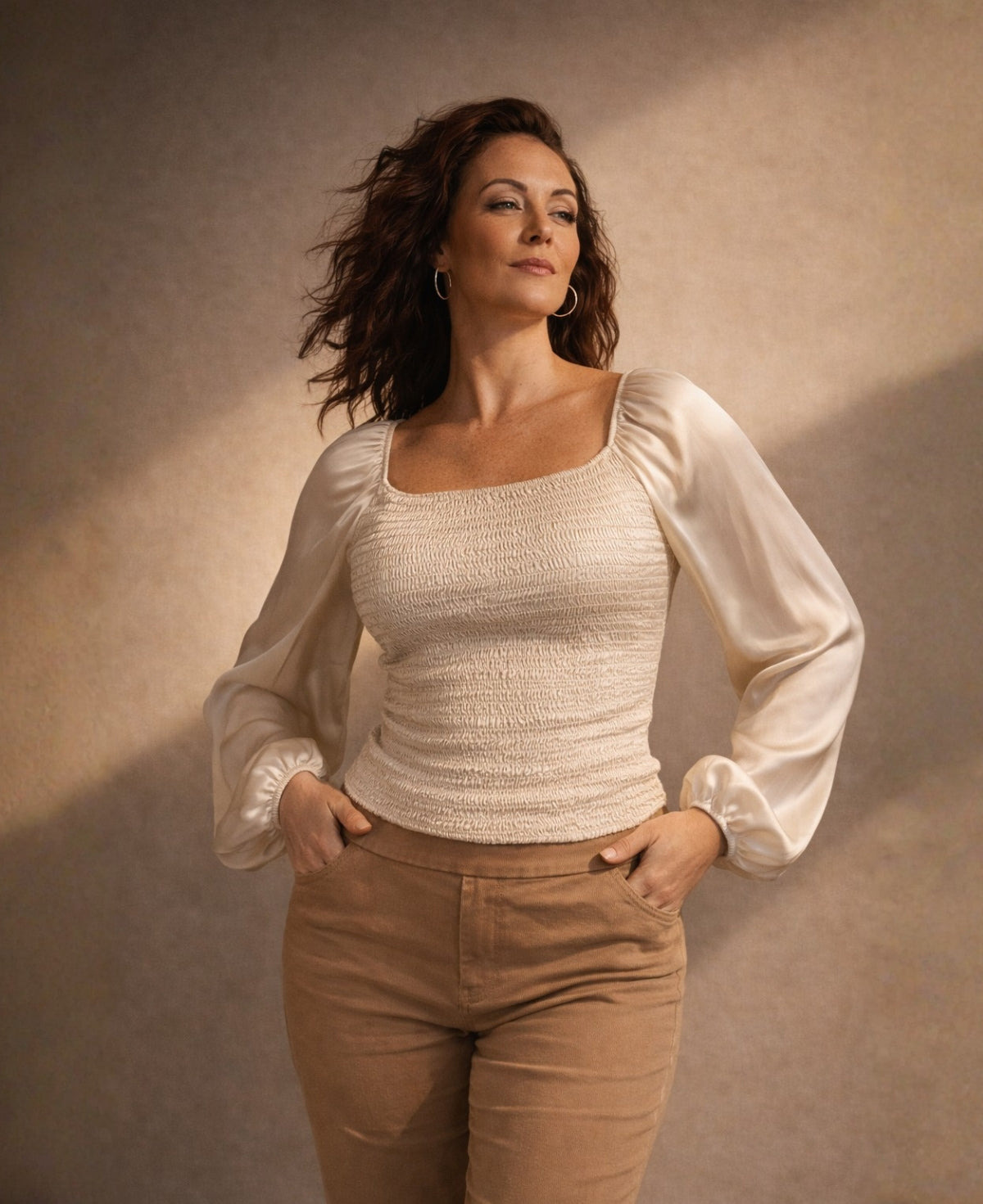 Editorial image of Shirred Satin Top in Oat styled in sculptural studio lighting, showcasing square neckline, textured shirring and satin sleeve sheen.