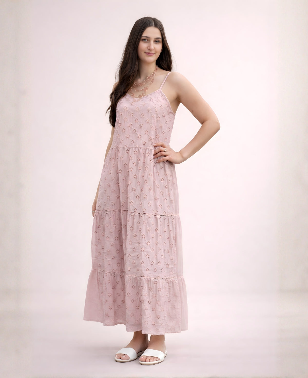 Woman wearing the Skylar Cotton Eyelet Dress in rose with thin straps and a tiered maxi skirt on a soft studio background
