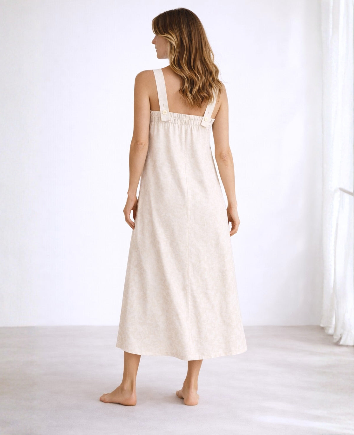 Back view of off-white jacquard maxi dress showing elasticated shirred back, adjustable overlapping straps, and full-length A-line fit