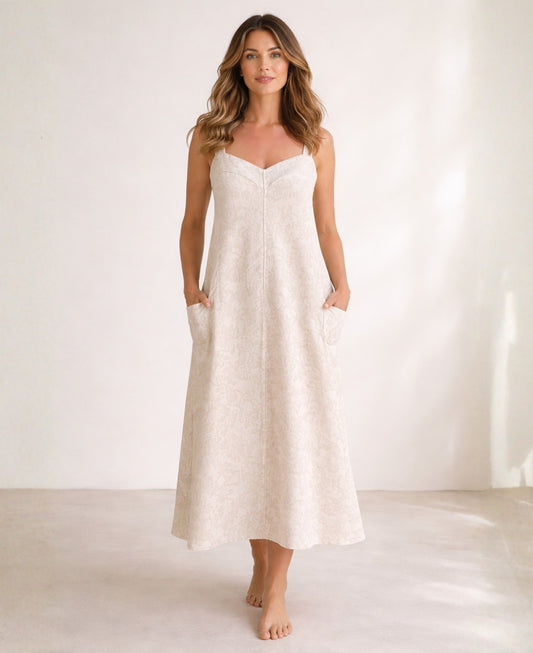 Front view of off-white sweetheart jacquard maxi dress with wide straps, central front seam, side pockets, and A-line silhouette, shown full length