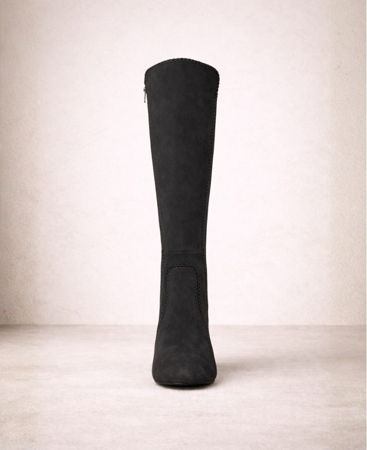Front view of black suede knee high boots with swept knee-high silhouette, refined stitching and structured shape