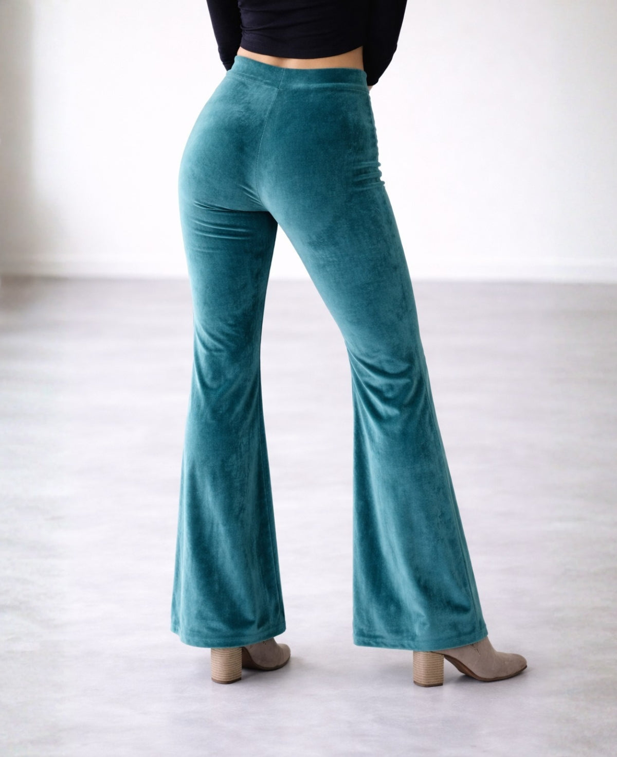 Back view detail of teal velour flare pants focusing on flared leg shape and velvet fabric texture