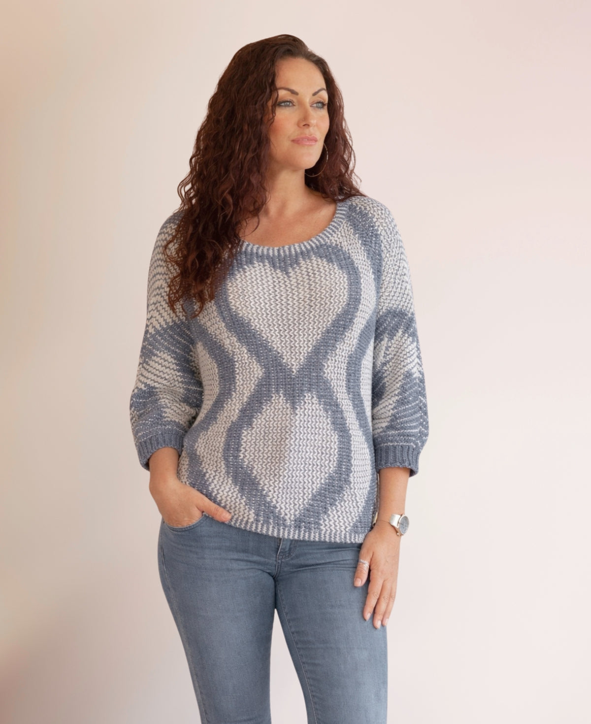 Model wearing the Valentine Wool Blend Jumper in Jeans blue with heart knit pattern, shown in a relaxed angled front pose against a neutral studio background.