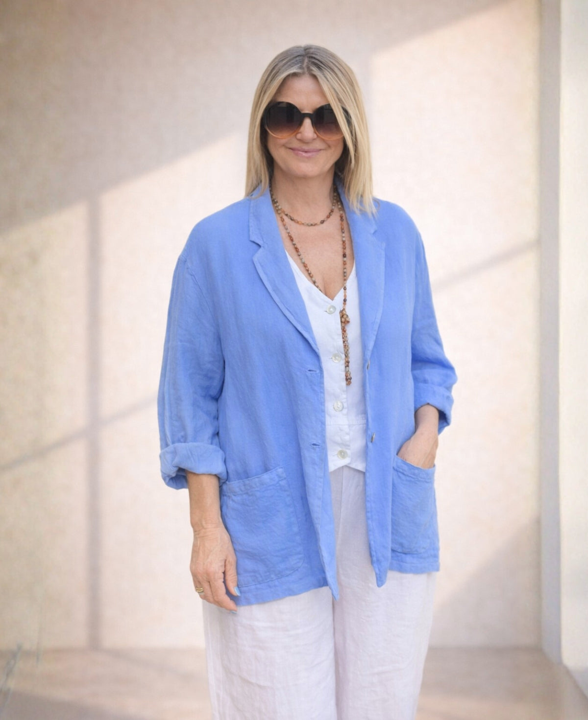 Iris blue linen blazer crafted from lightweight fabric, featuring a relaxed fit, double-button closure, and practical pockets for a refined summer look.