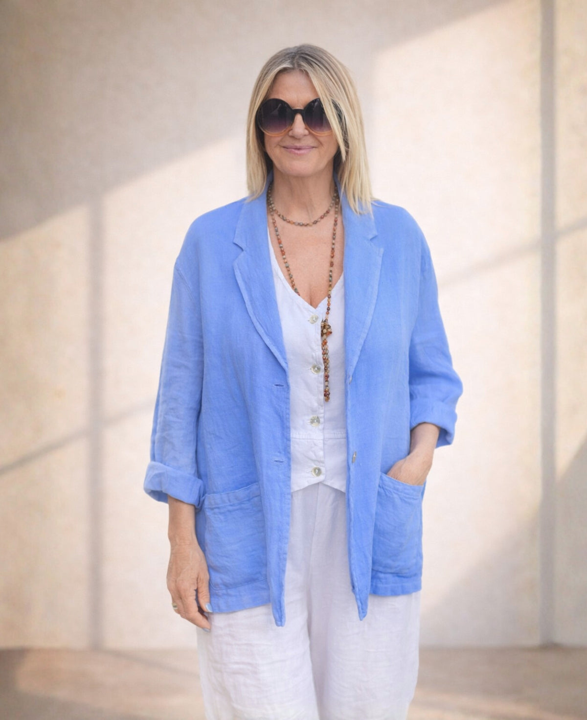 Iris blue linen blazer crafted from lightweight fabric, featuring a relaxed fit, double-button closure, and practical pockets for a refined summer look.