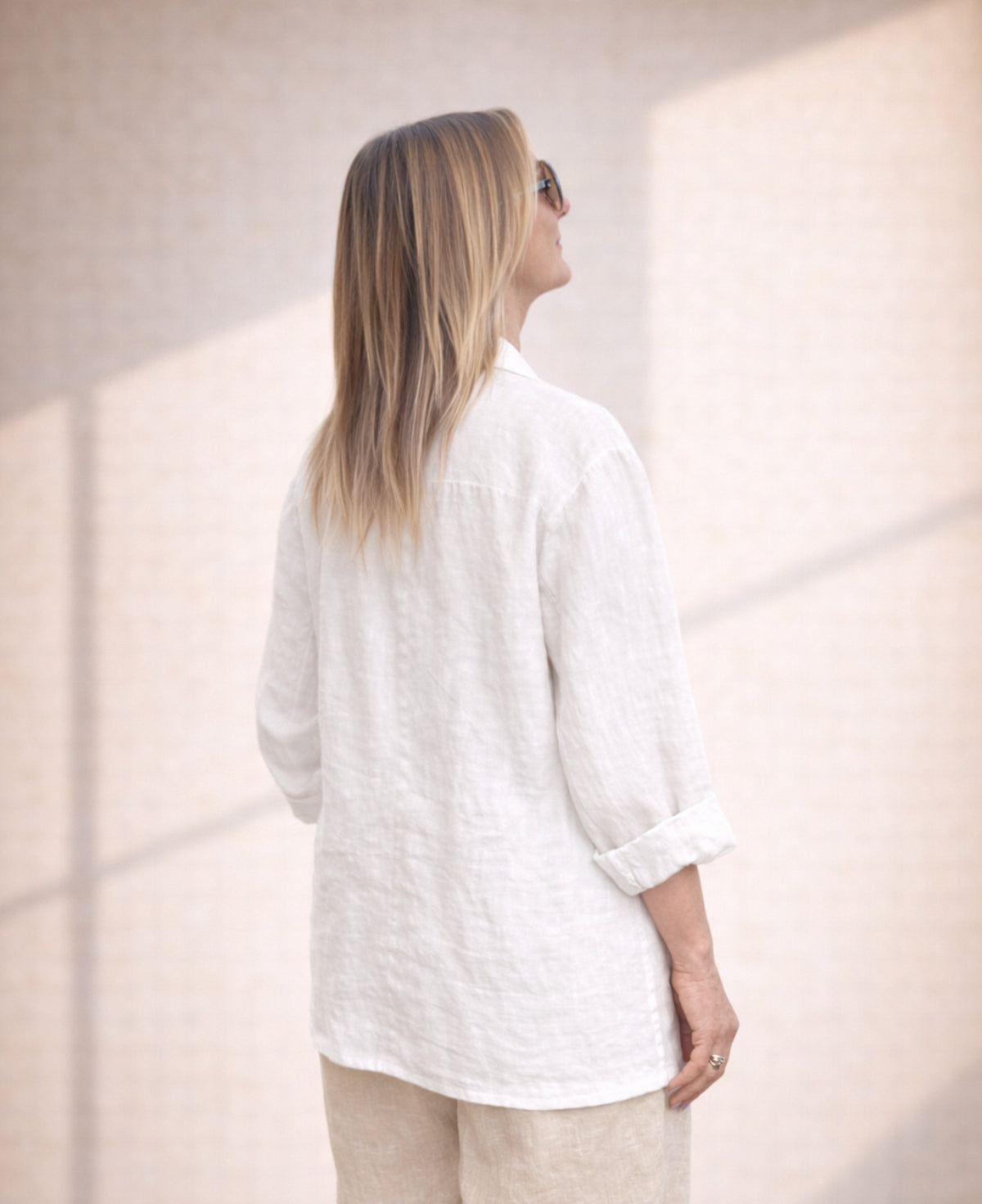 White linen blazer crafted from lightweight fabric, featuring a relaxed fit, double-button closure, and practical pockets for a refined summer look.