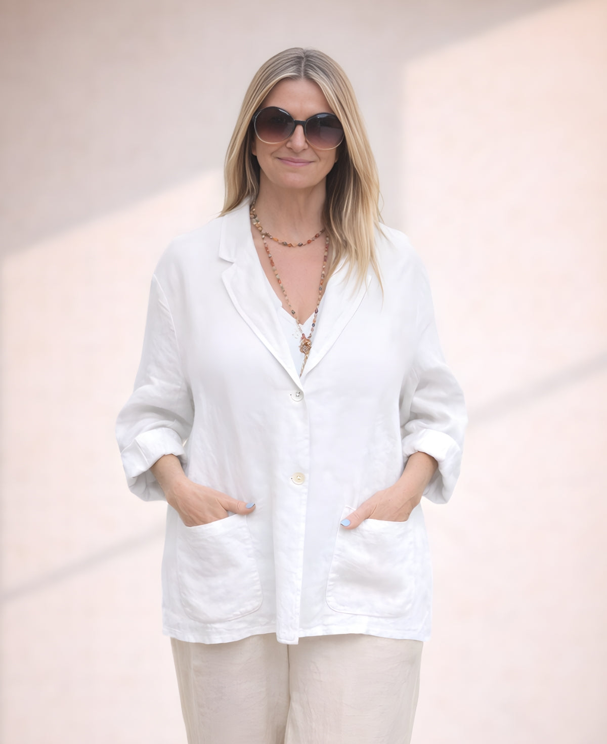 White linen blazer crafted from lightweight fabric, featuring a relaxed fit, double-button closure, and practical pockets for a refined summer look.