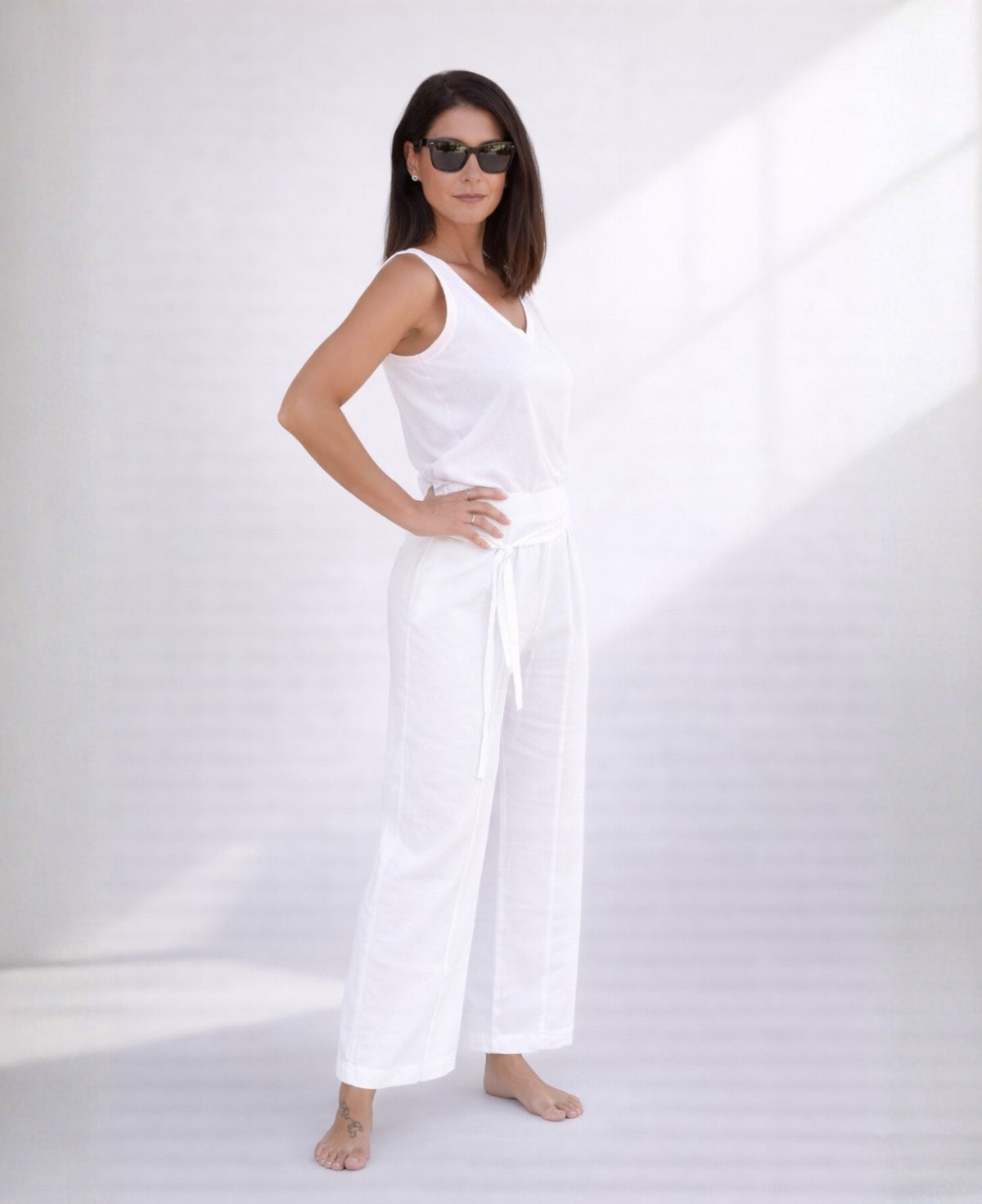 Woman wearing white linen palazzo pants in a front angled view, featuring a wide leg silhouette, stretch waist, and lightweight breathable linen fabric.
