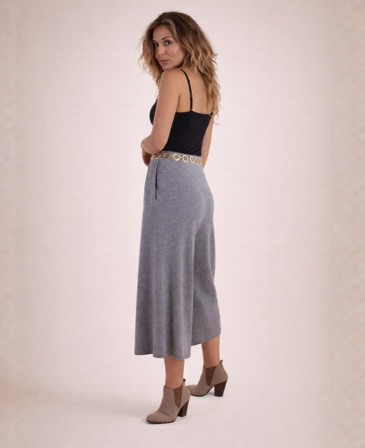 Back angled view of cool grey Winter Knit Culottes styled with a black tank top, gold circle belt and ankle boots.