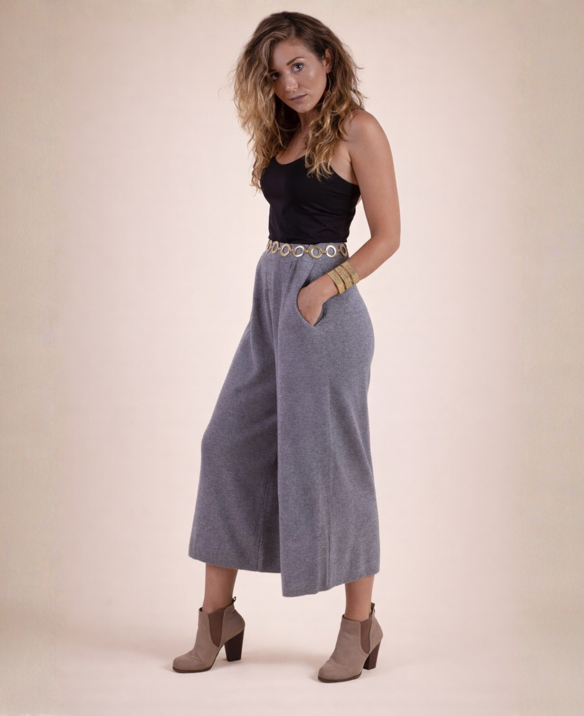 Side view of cool grey Winter Knit Culottes worn with a black tank top, gold circle belt and ankle boots.