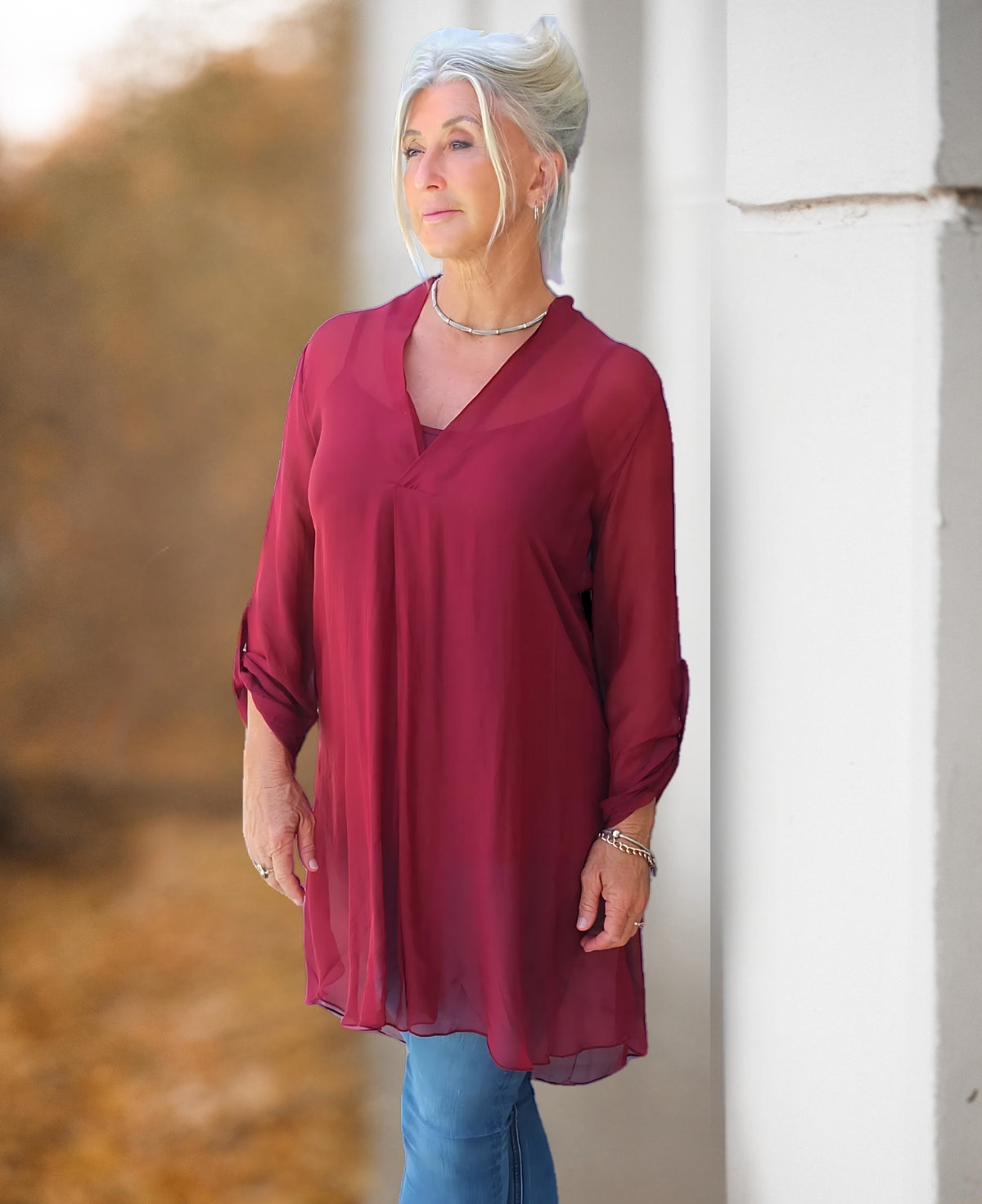 April long silk top in wine colour shown front view with flowy shape and longline silhouette in natural outdoor setting