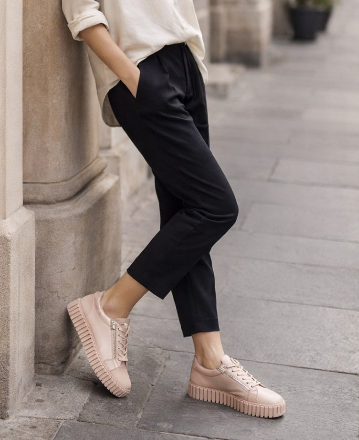 Woman wearing Bump Rose leather sneakers with cropped trousers in a soft urban city setting