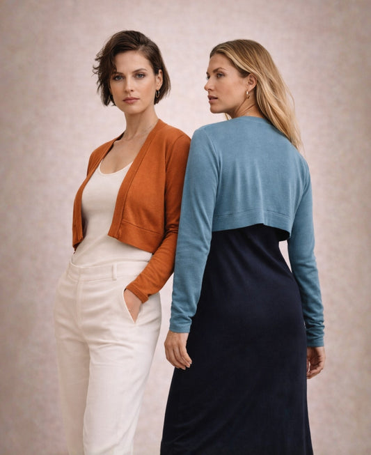Two women wearing rust and blue teal Nell boleros styled in a modern fashion editorial showing front and back views on a soft neutral background