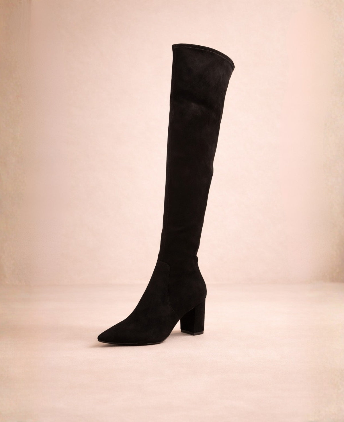 Black thigh-high boots in microsuede with pointed toe and structured block heel shown from a front angled perspective.