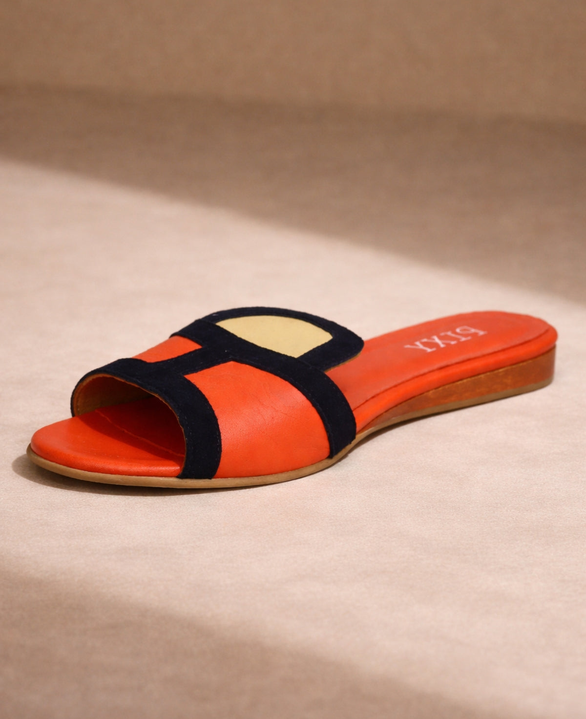 PIXY Dion leather slide sandal in coral and navy shown from front angle on warm neutral background