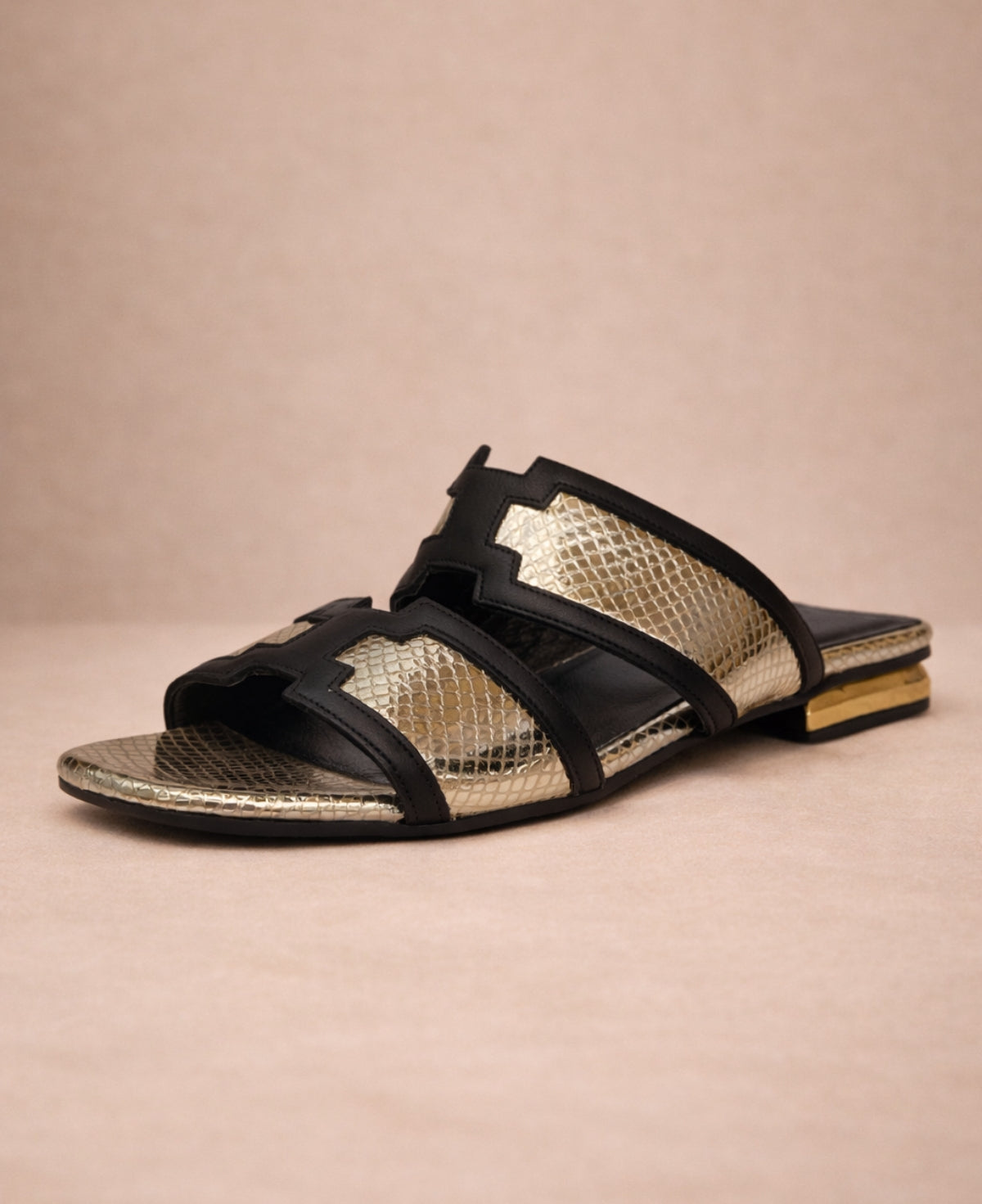 Silvery metallic gold snakeskin slide sandals for women front angle with black leather trim and flat sole