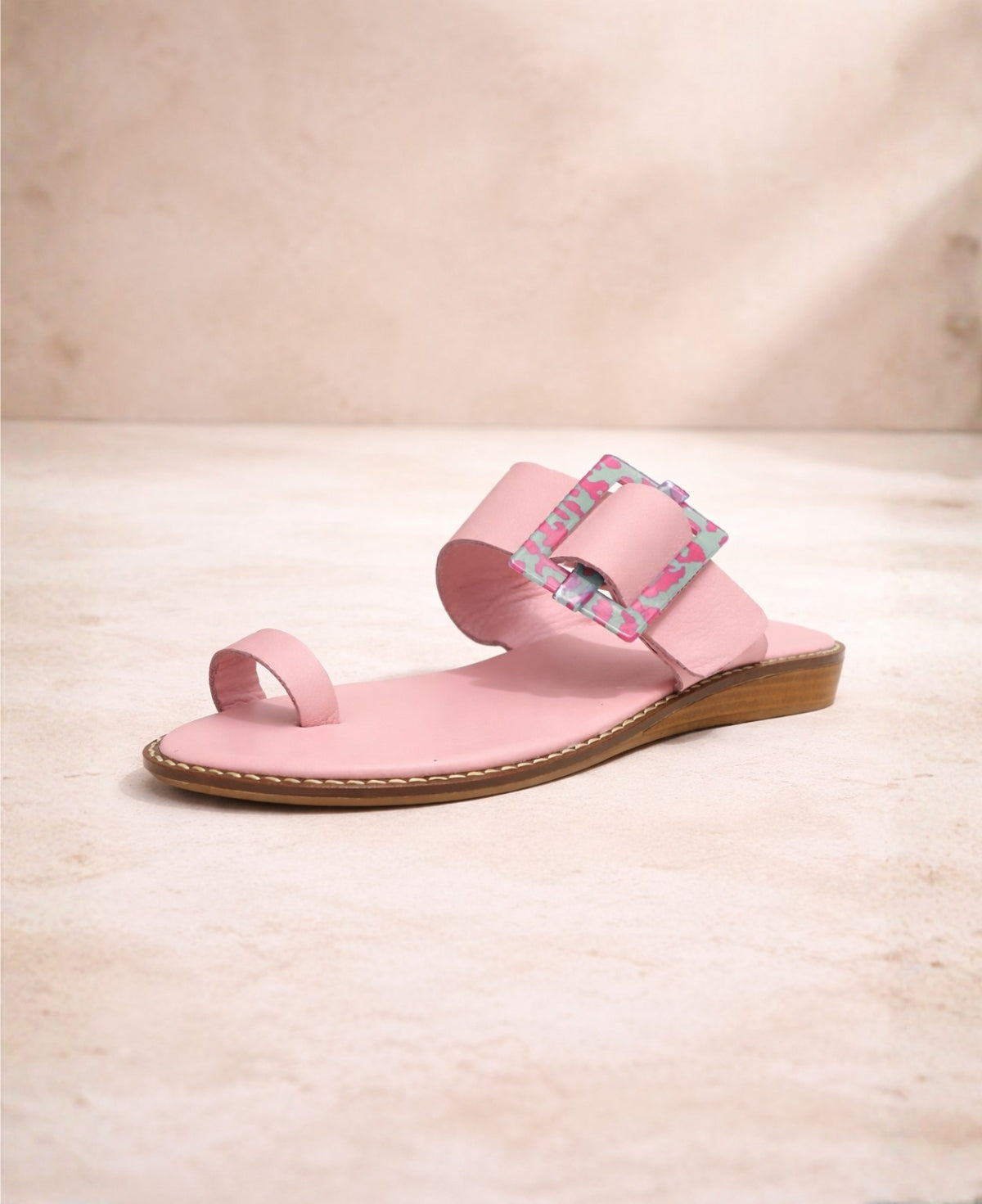 Pink leather buckle sandal close-up showing adjustable strap and patterned buckle