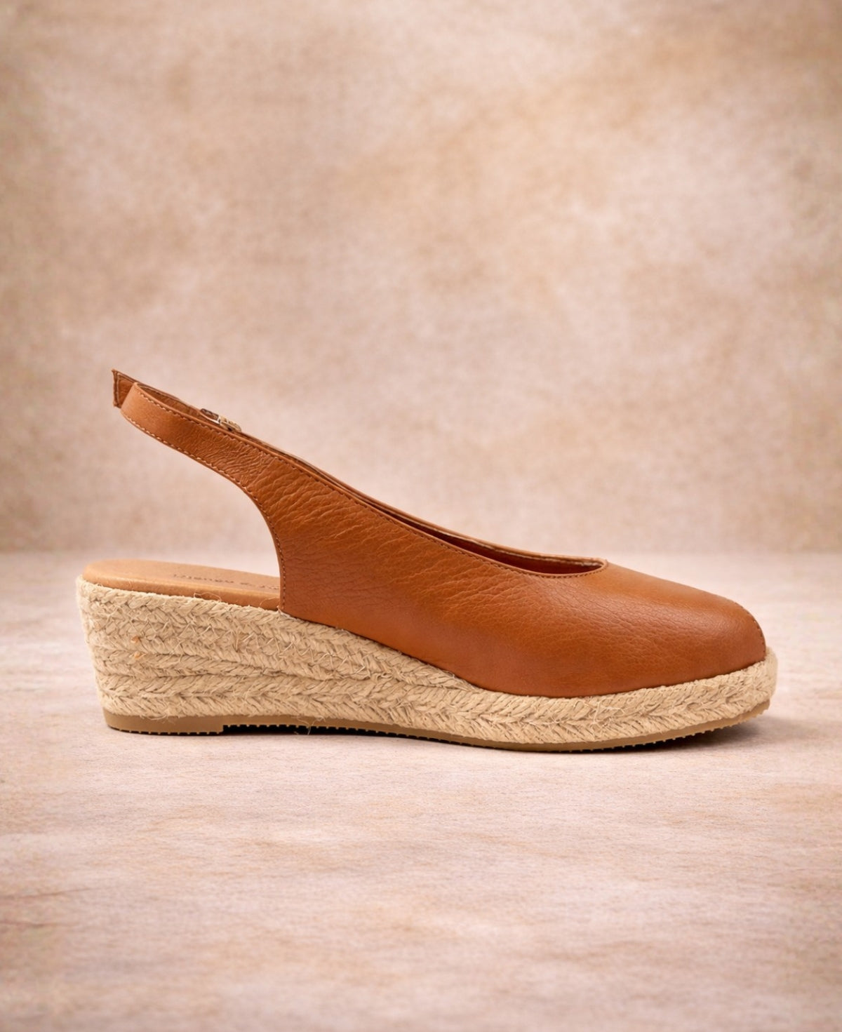 Inner side view of tan leather espadrille wedge sandal highlighting smooth leather upper and jute wedge