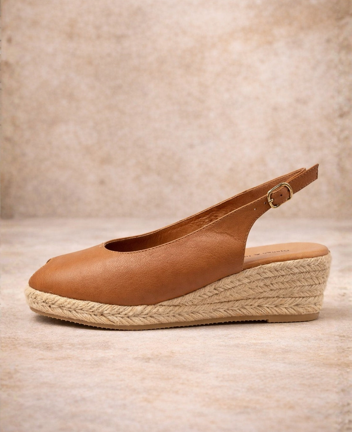 Outer side view of tan leather espadrille wedge sandal with buckle strap and low jute wedge heel