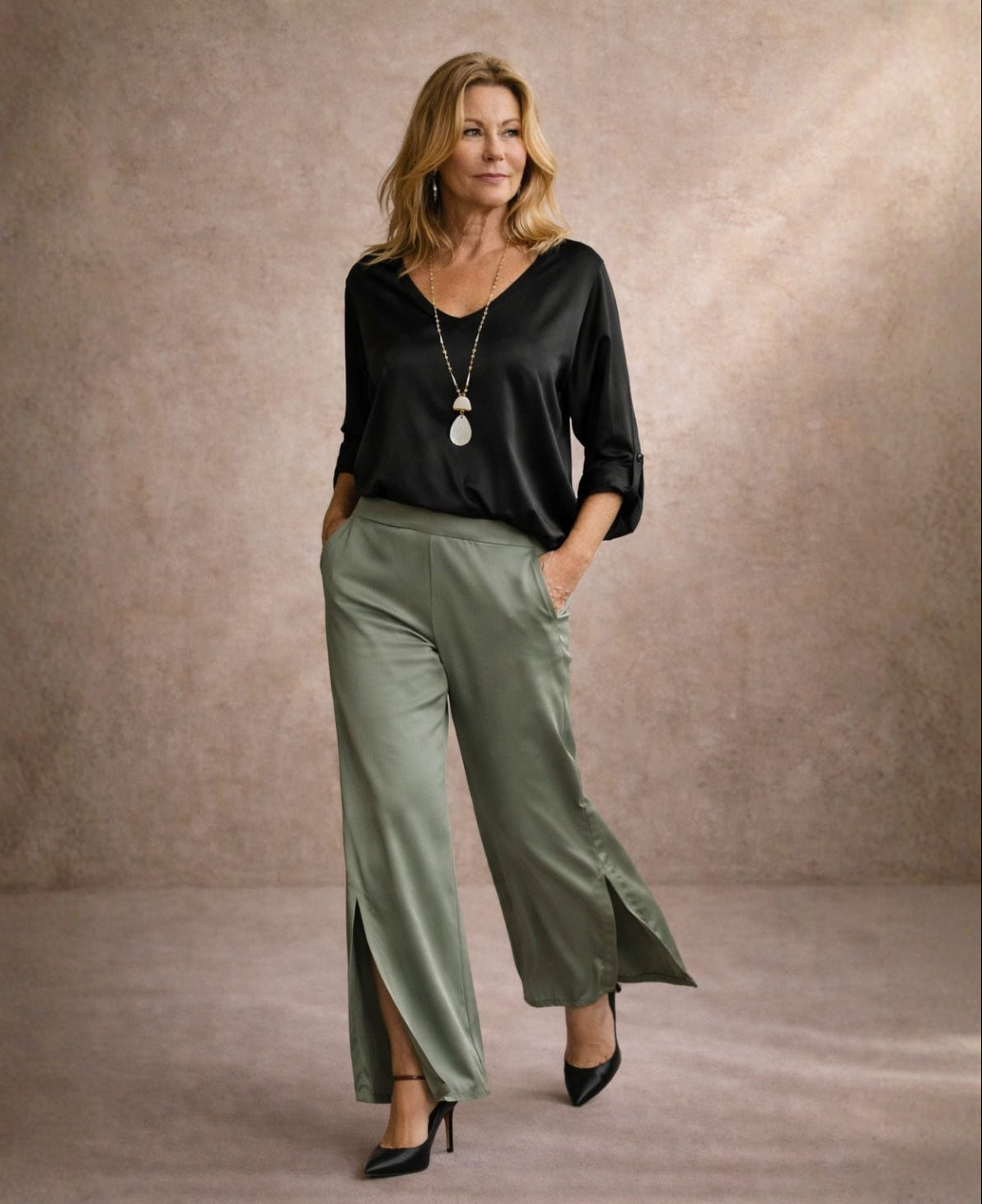 Camel satin wide leg pants with side split styled with black satin top in editorial walking pose