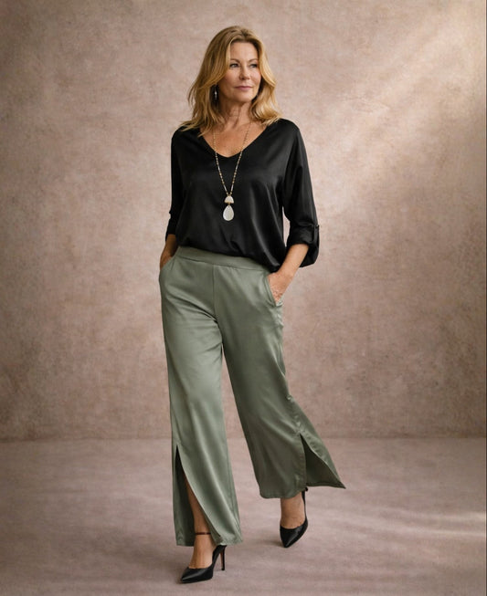 Camel satin wide leg pants with side split styled with black satin top in editorial walking pose