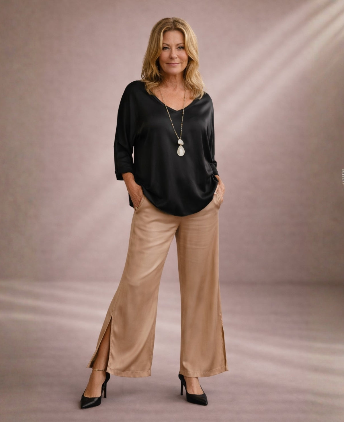 Camel satin wide leg pants with side split styled with black satin top in editorial walking pose
